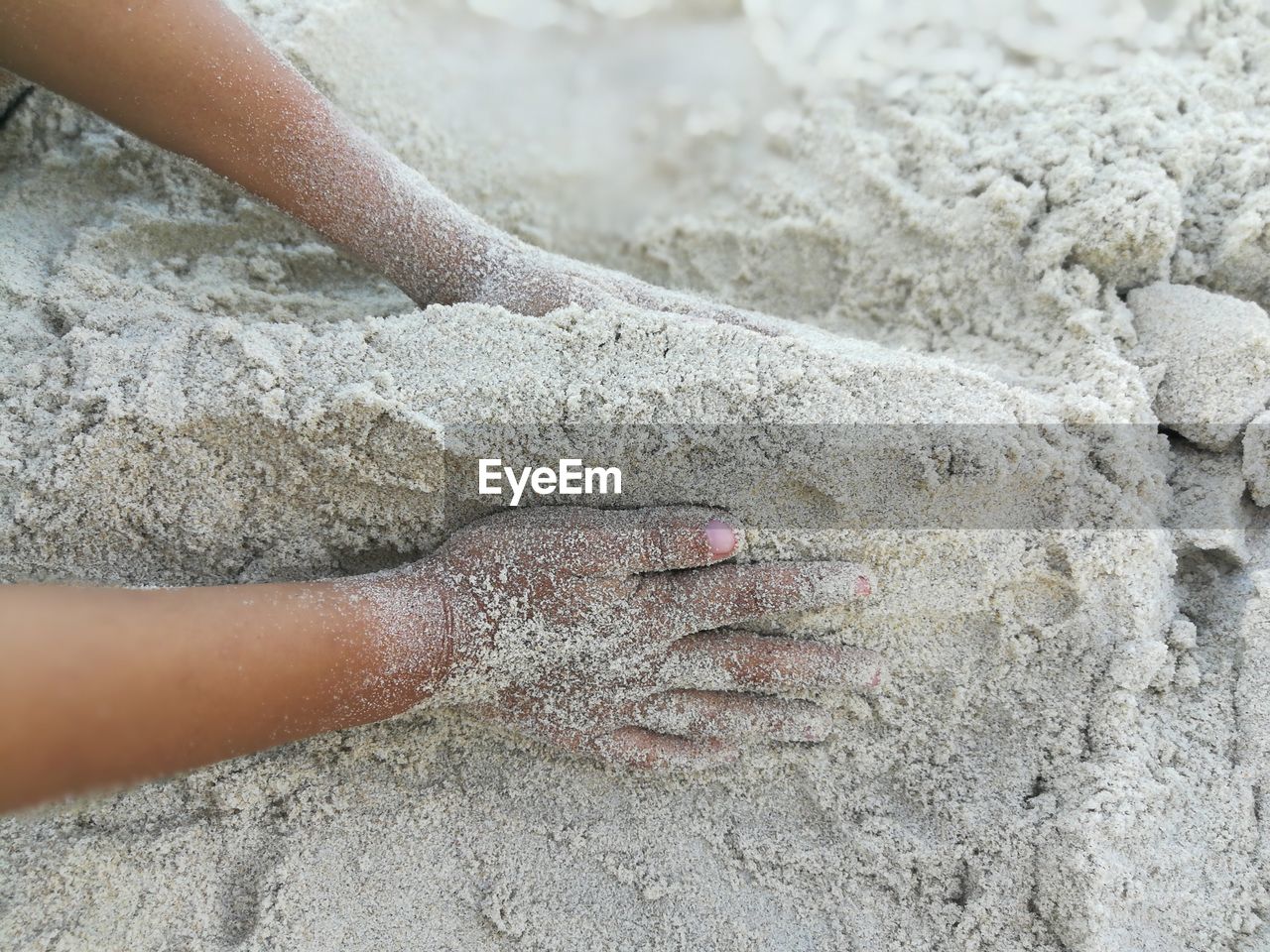 Cropped hands making sandcastle at beach