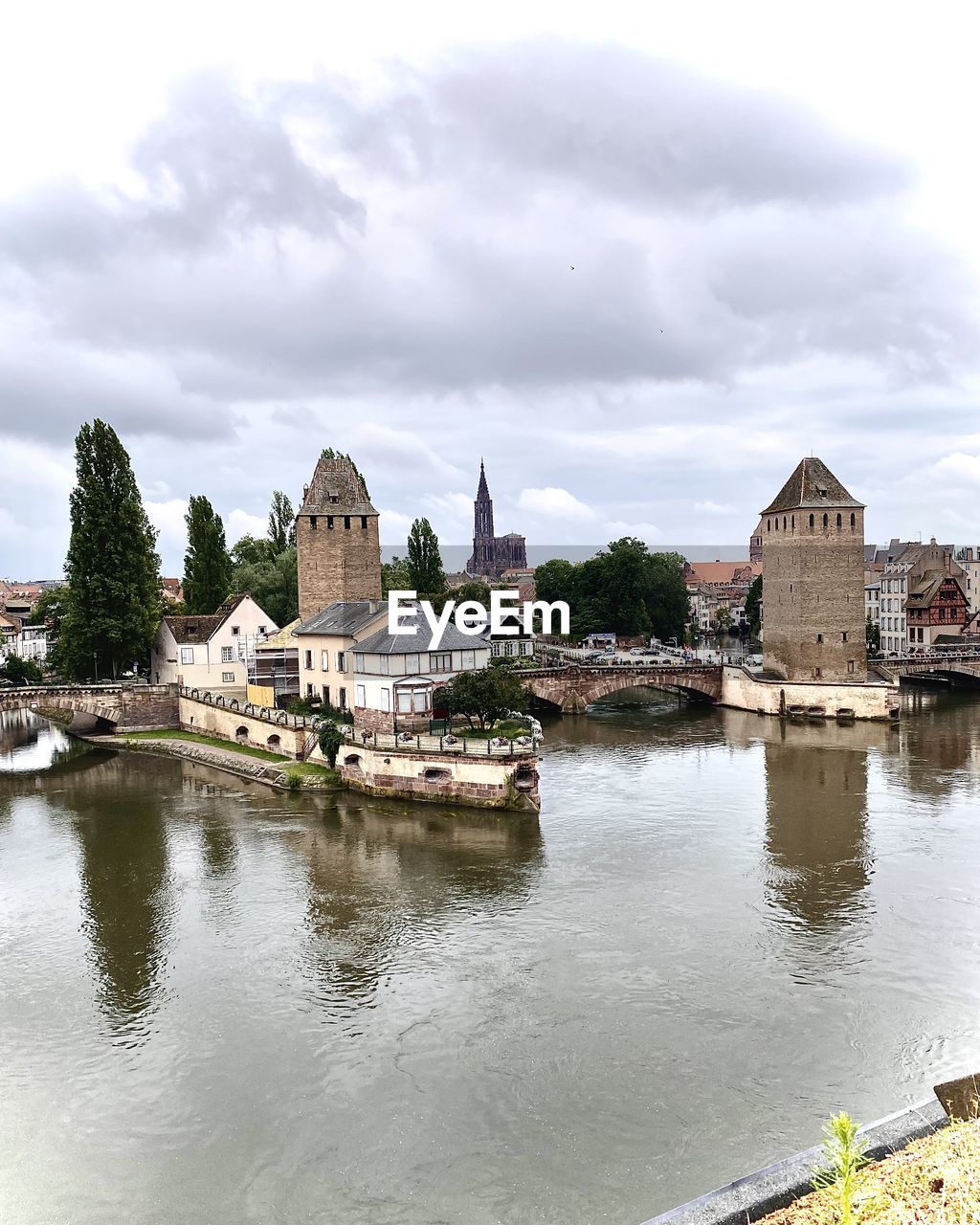 Buildings at waterfront against cloudy sky