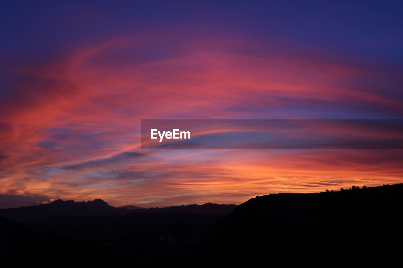 SCENIC VIEW OF SILHOUETTE MOUNTAIN AGAINST DRAMATIC SKY