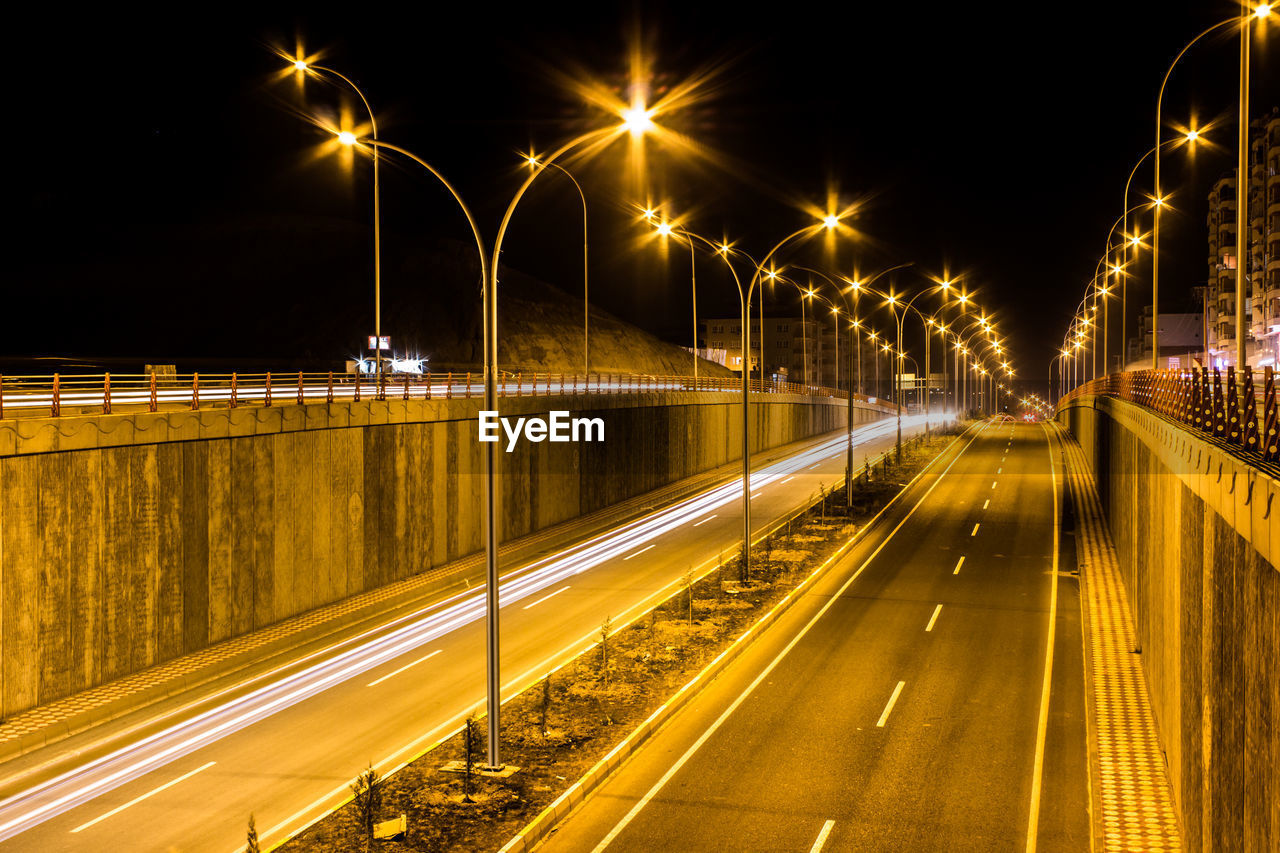 Light trails on road against sky at night