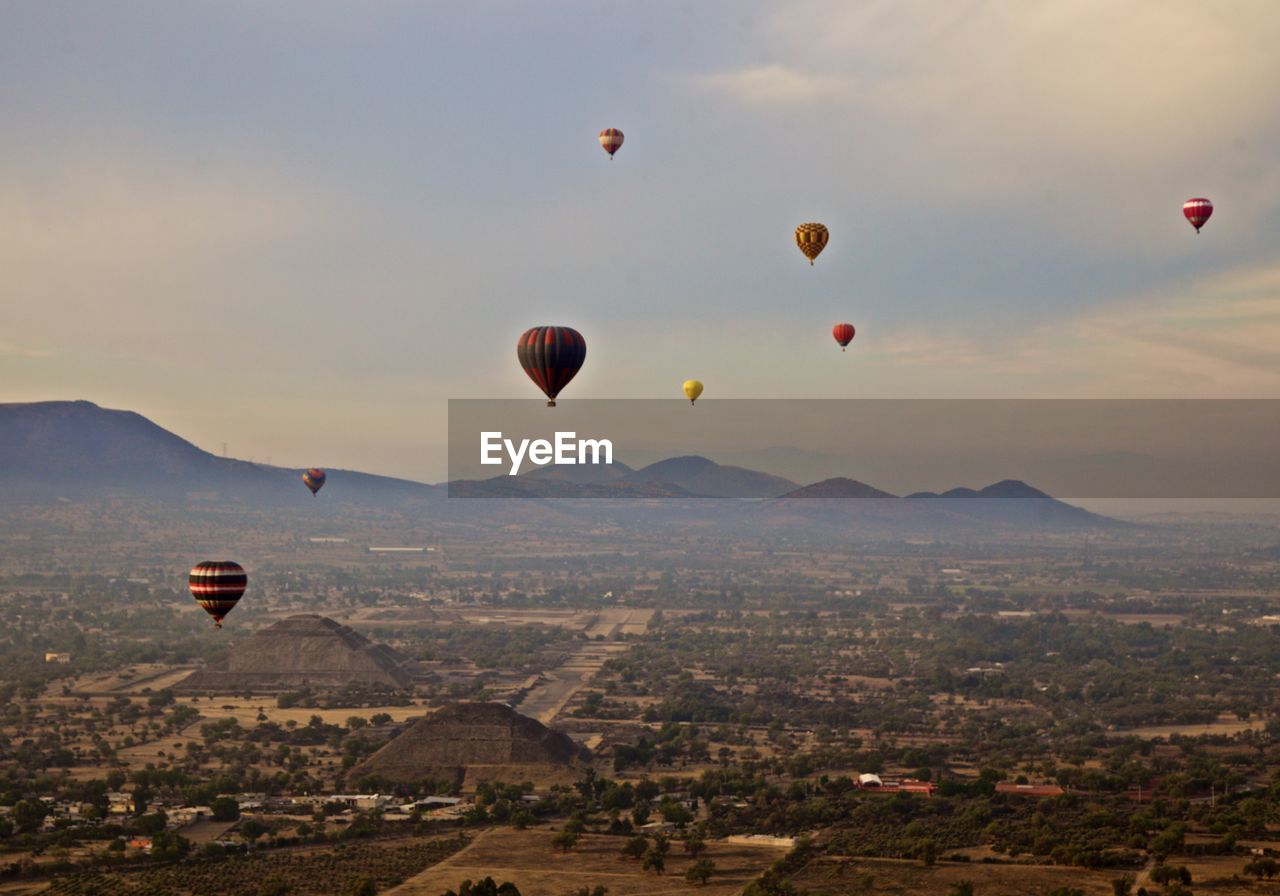 High angle view of hot air balloons flying over landscape