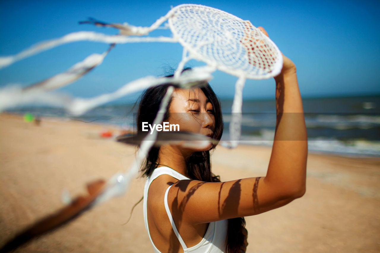 Asian girl holding dream catcher on beach