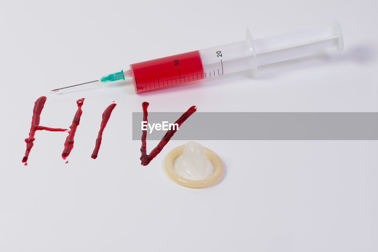 Close-up of hiv in blood by syringe over white background