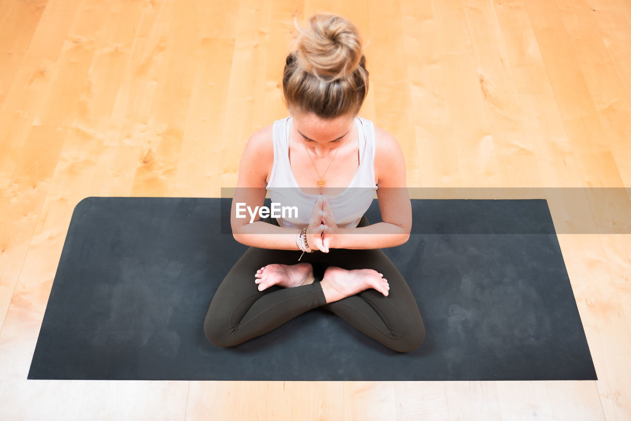 High angle view of woman mediating on exercise mat