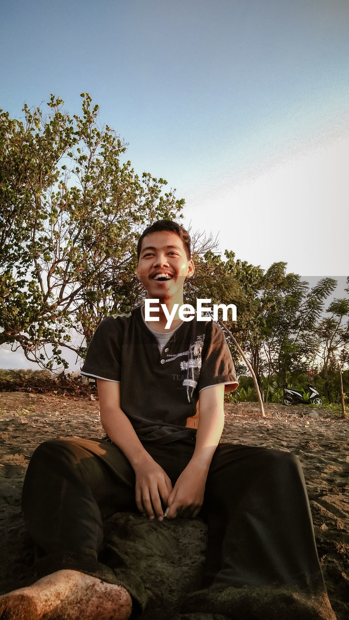 Portrait of smiling man sitting against sky