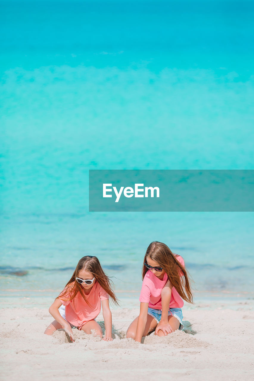 Sisters plying with sand on beach