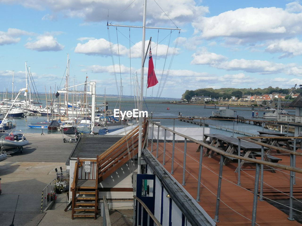 SAILBOATS MOORED ON HARBOR AGAINST SKY