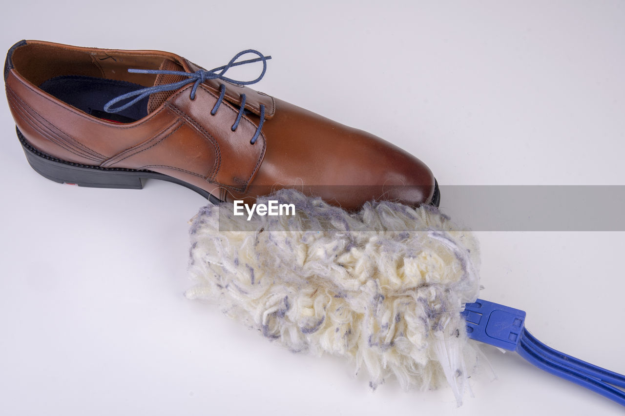High angle view of cleaning equipment and shoe over white background
