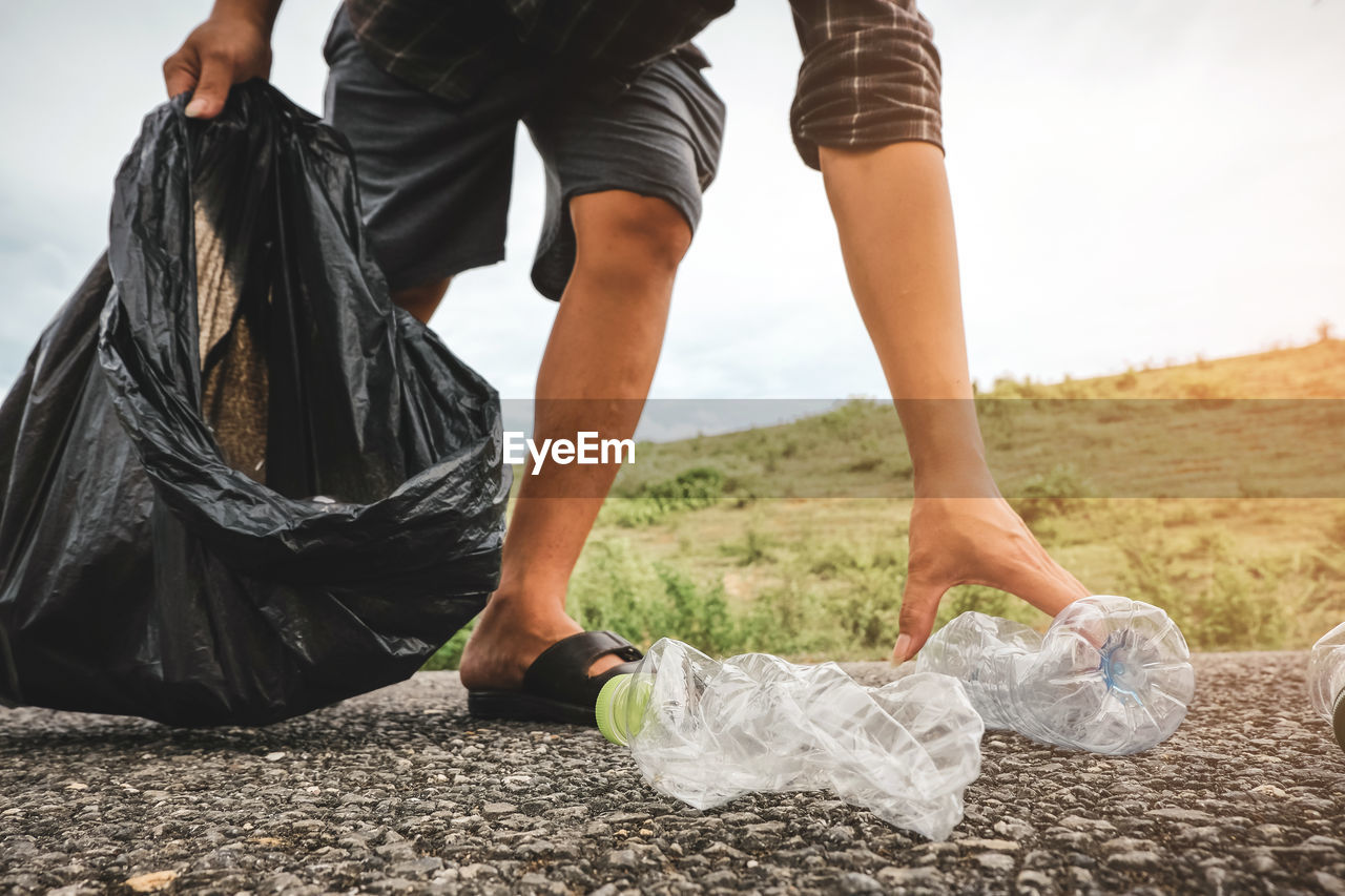 Low section of man collecting garbage on land