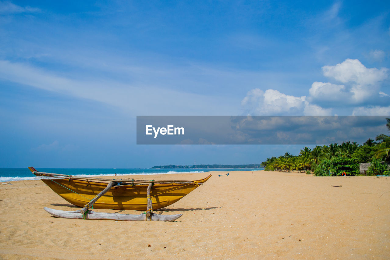 LOUNGE CHAIRS ON BEACH AGAINST SKY