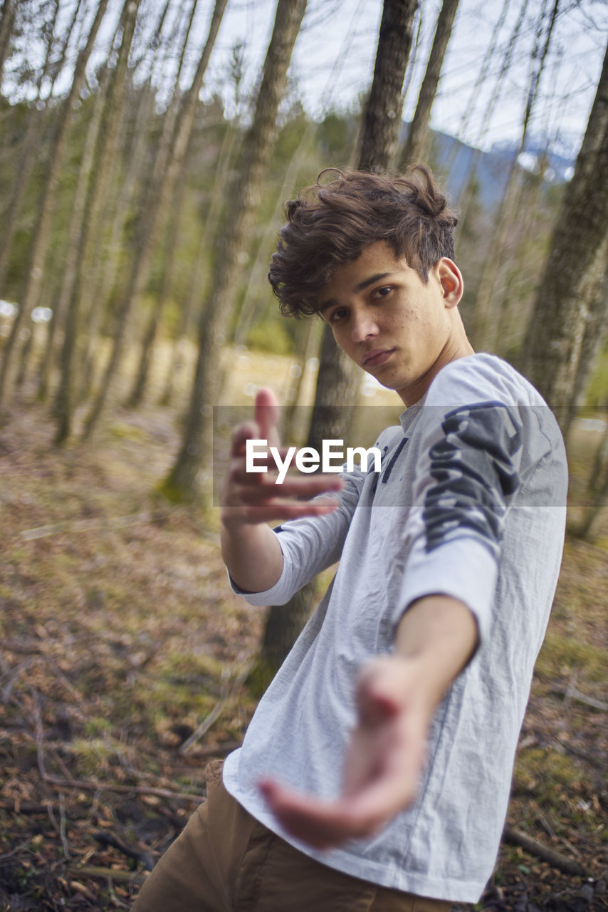 Portrait of young man standing at forest