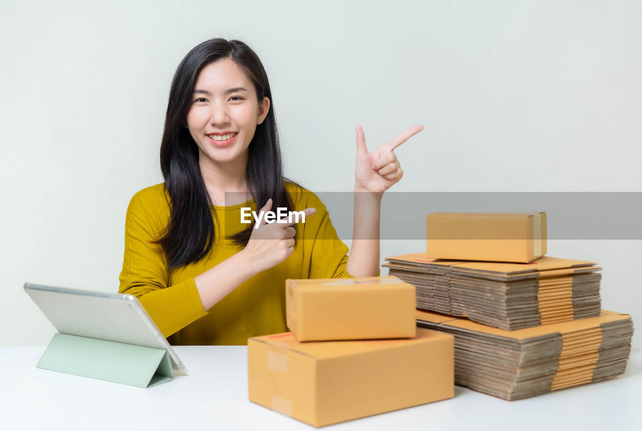 PORTRAIT OF A SMILING YOUNG WOMAN SITTING ON STACK OF A HAND