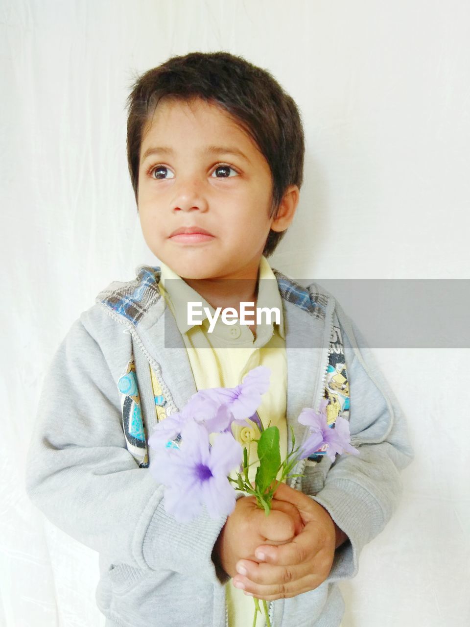 He is standing with a sweet boy and a beautiful pose with a bouquet of flowers in hand 