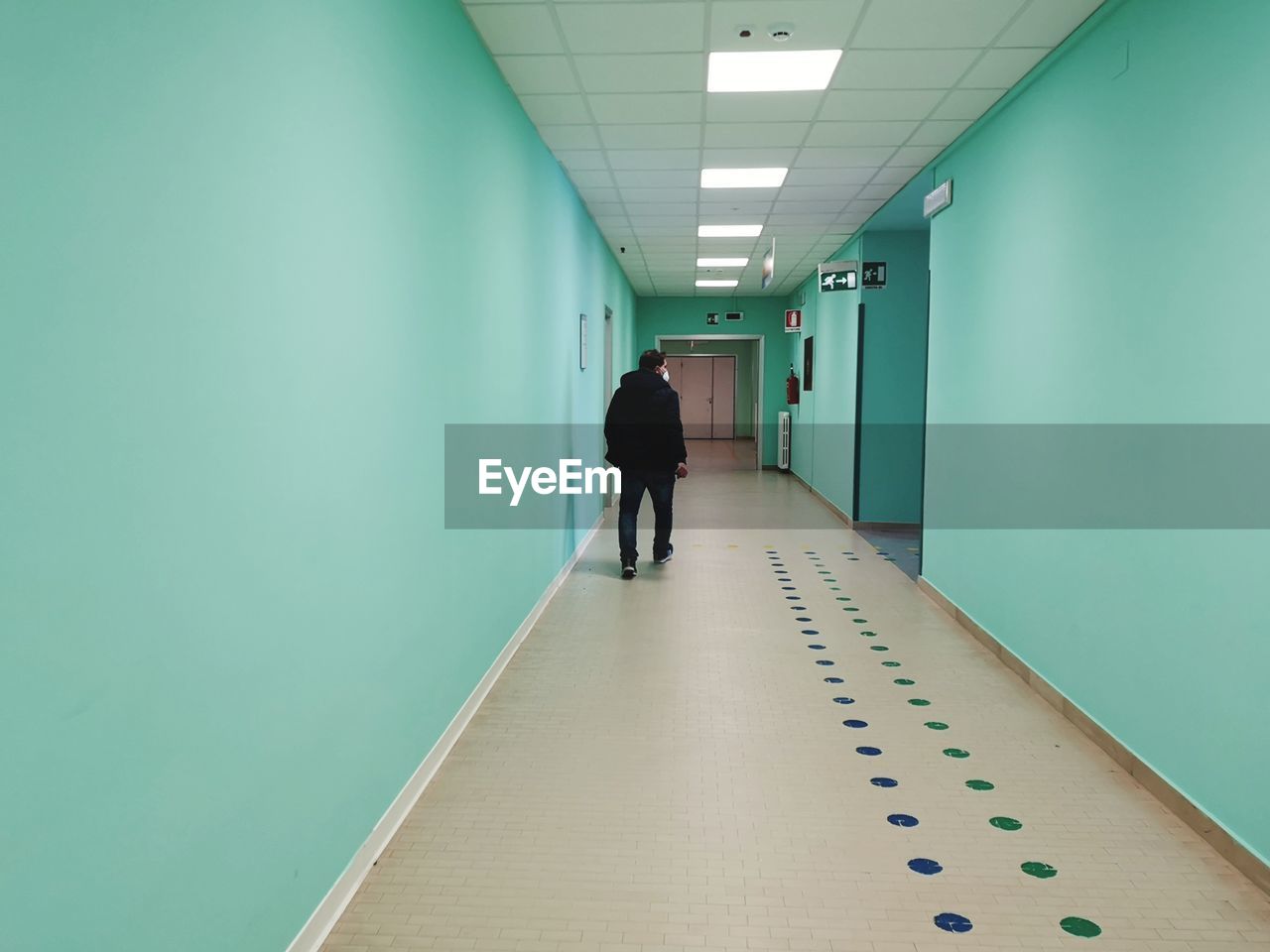 arcade, corridor, indoors, adult, full length, architecture, one person, building, walking, men, hospital, healthcare and medicine, rear view, the way forward, copy space, business, floor, occupation, room, hall