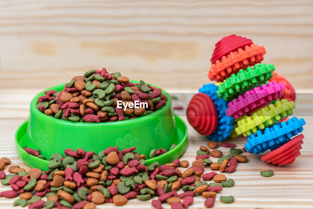 Pet food with rubber toy on wooden background