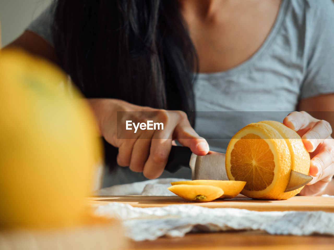 Midsection of woman cutting orange on board