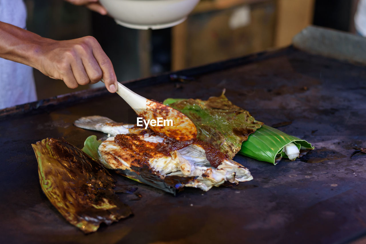 Cropped hands of person preparing fish on table