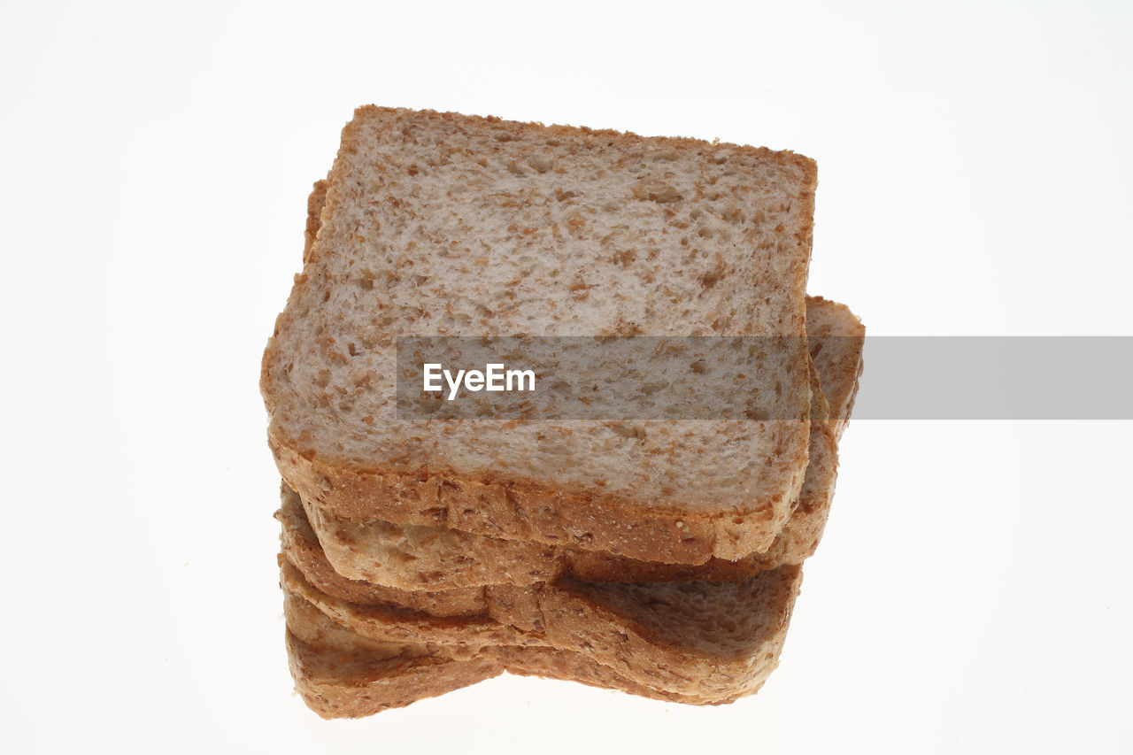 Close-up of brown breads stacked against white background