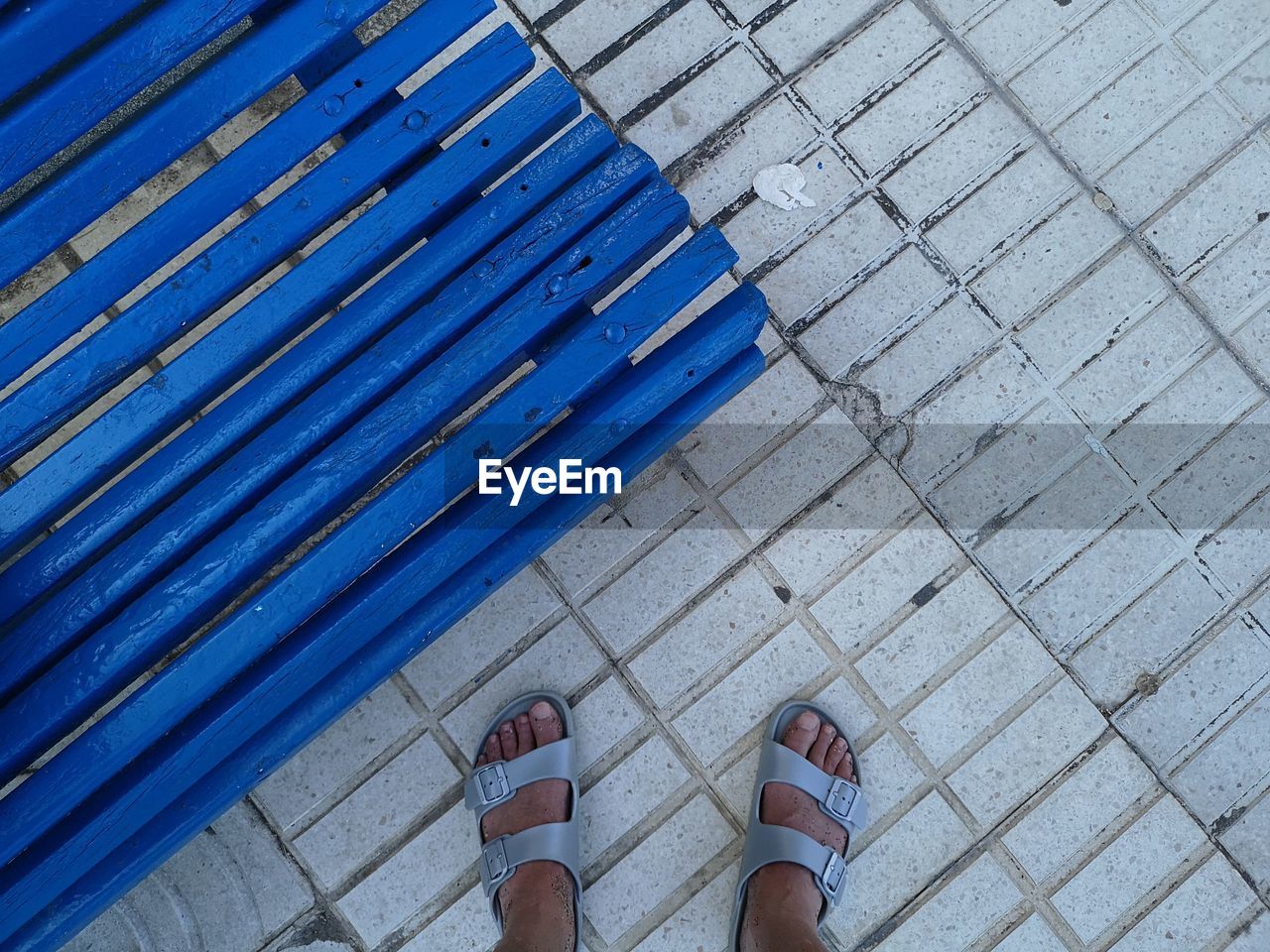 Low section of woman by blue bench on footpath