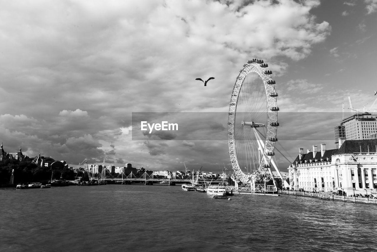 Ferris wheel in city against cloudy sky