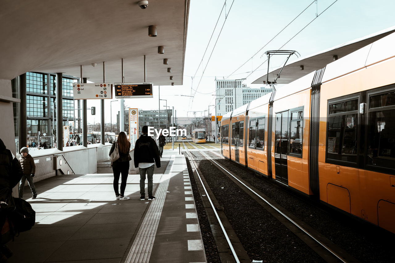 PEOPLE AT RAILROAD STATION IN CITY