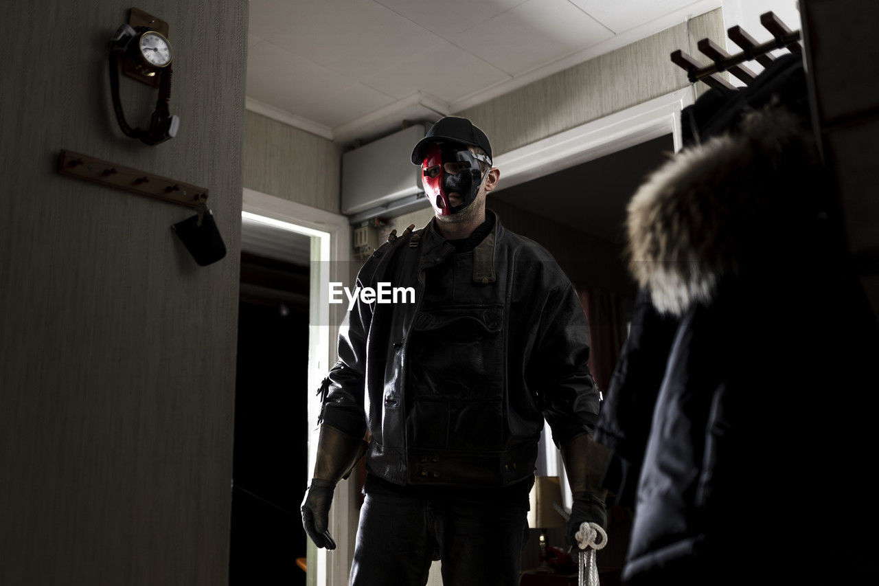 Demon wearing mask standing by doorway in cabin