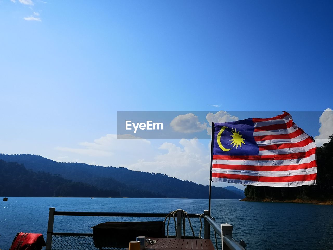 SCENIC VIEW OF FLAG ON SEA AGAINST MOUNTAIN