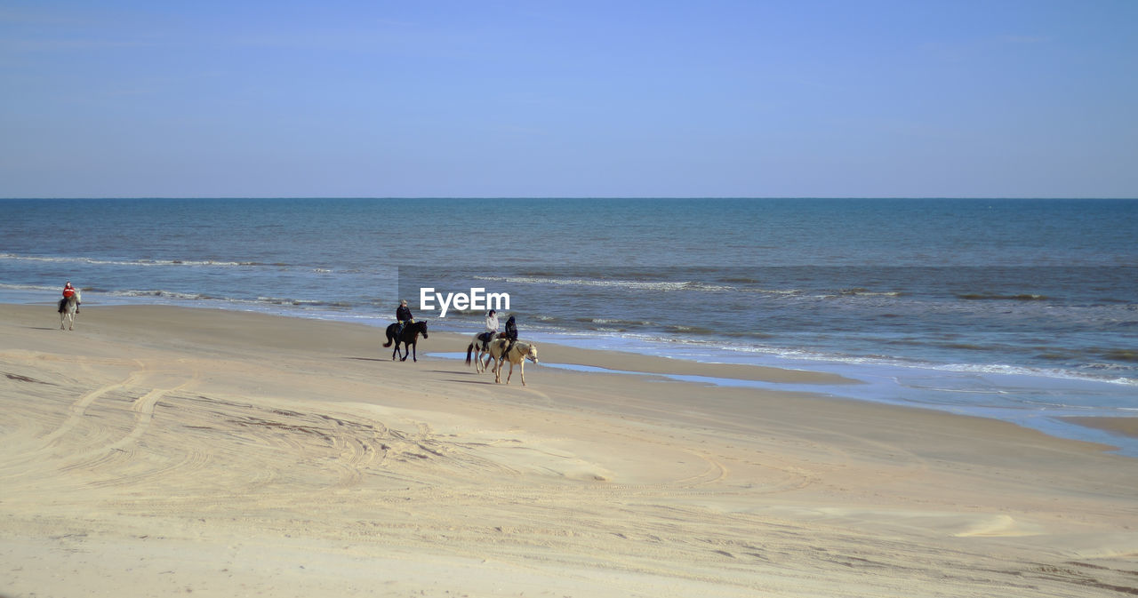 PEOPLE AT BEACH AGAINST SKY