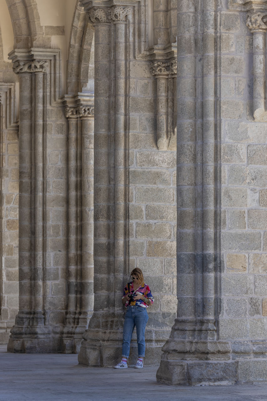 FULL LENGTH OF WOMAN STANDING IN FRONT OF COLONNADE