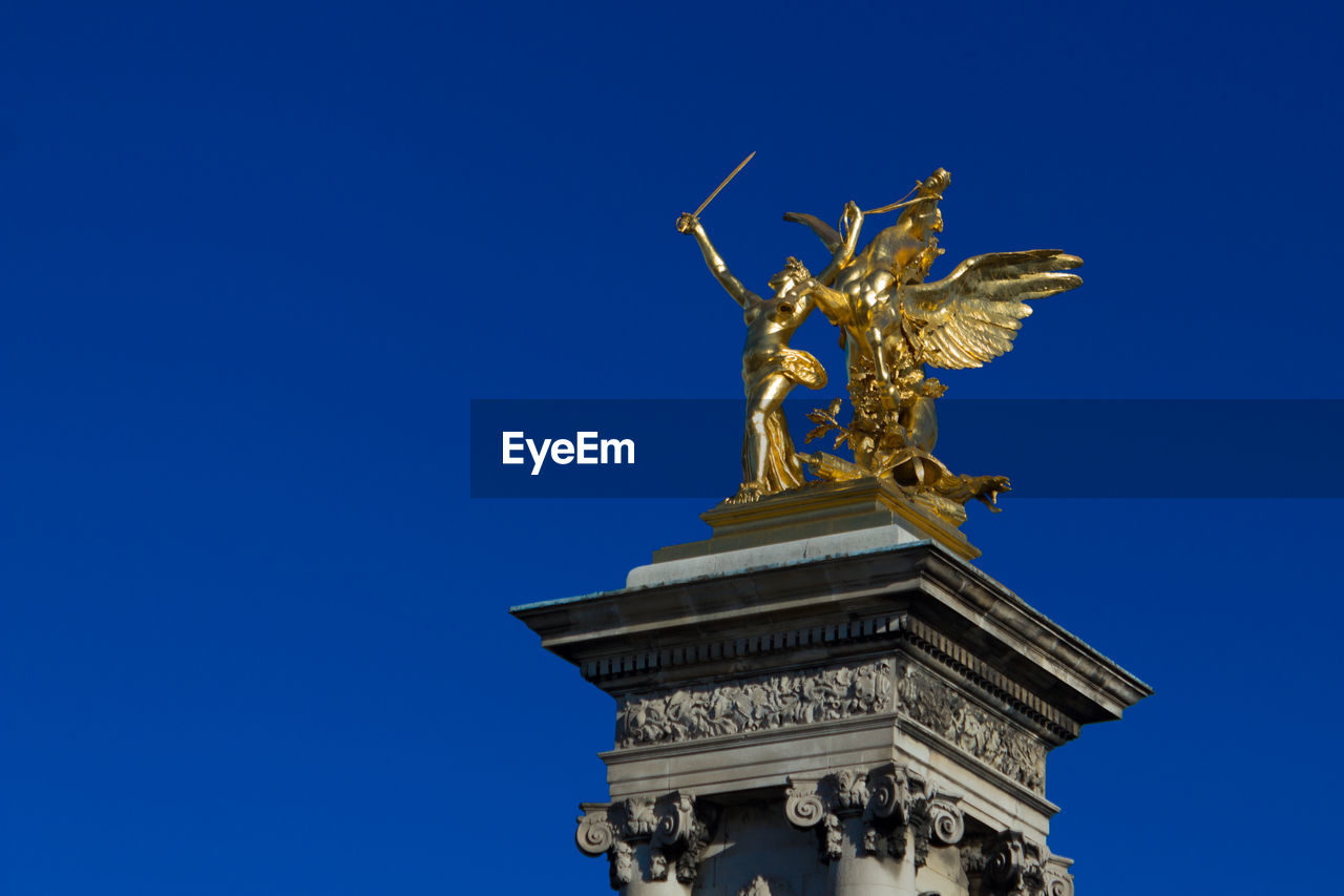 Low angle view of gold statue against clear blue sky at pont alexandre iii