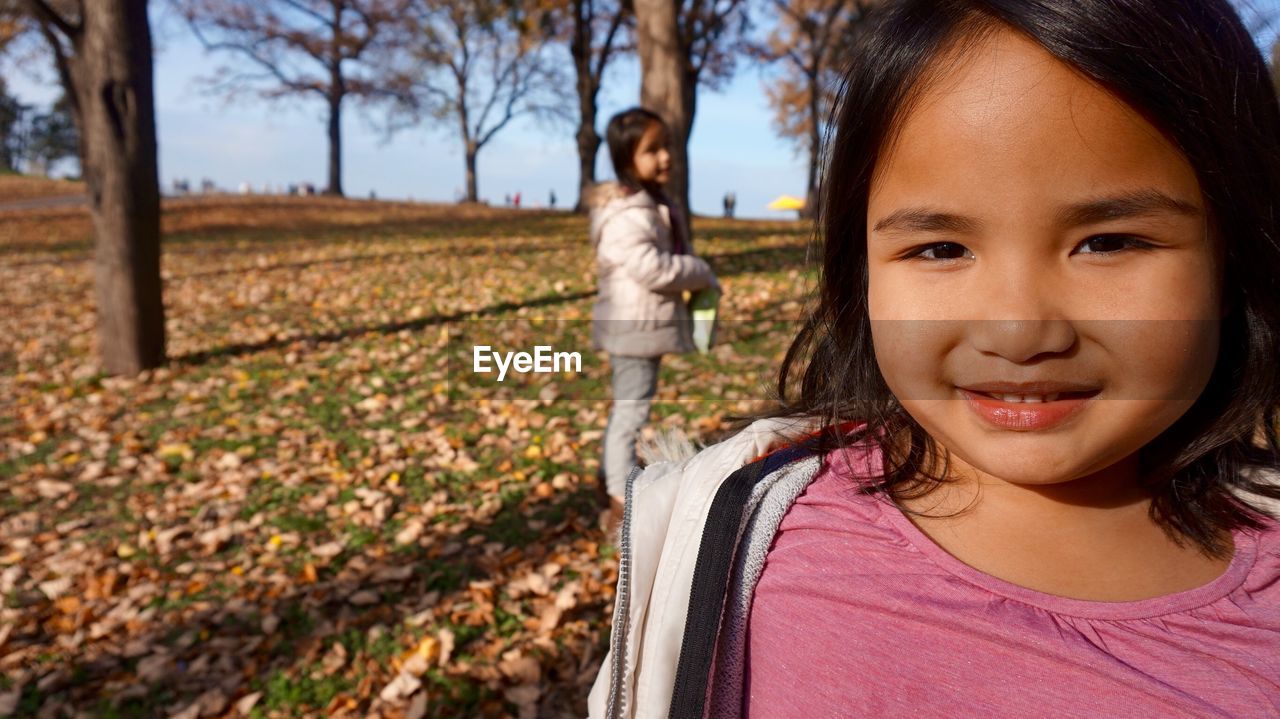 Portrait of girl standing on grassy field during autumn