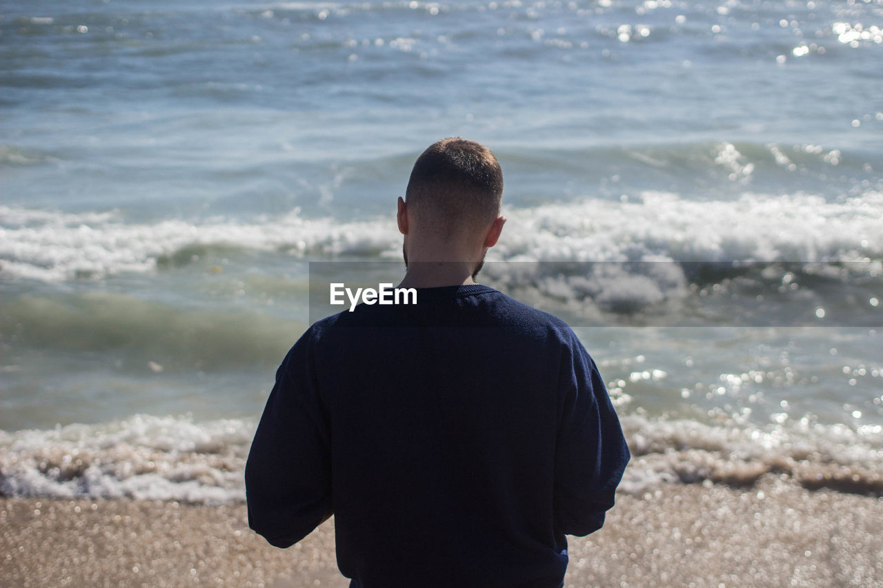 Rear view of man standing at beach