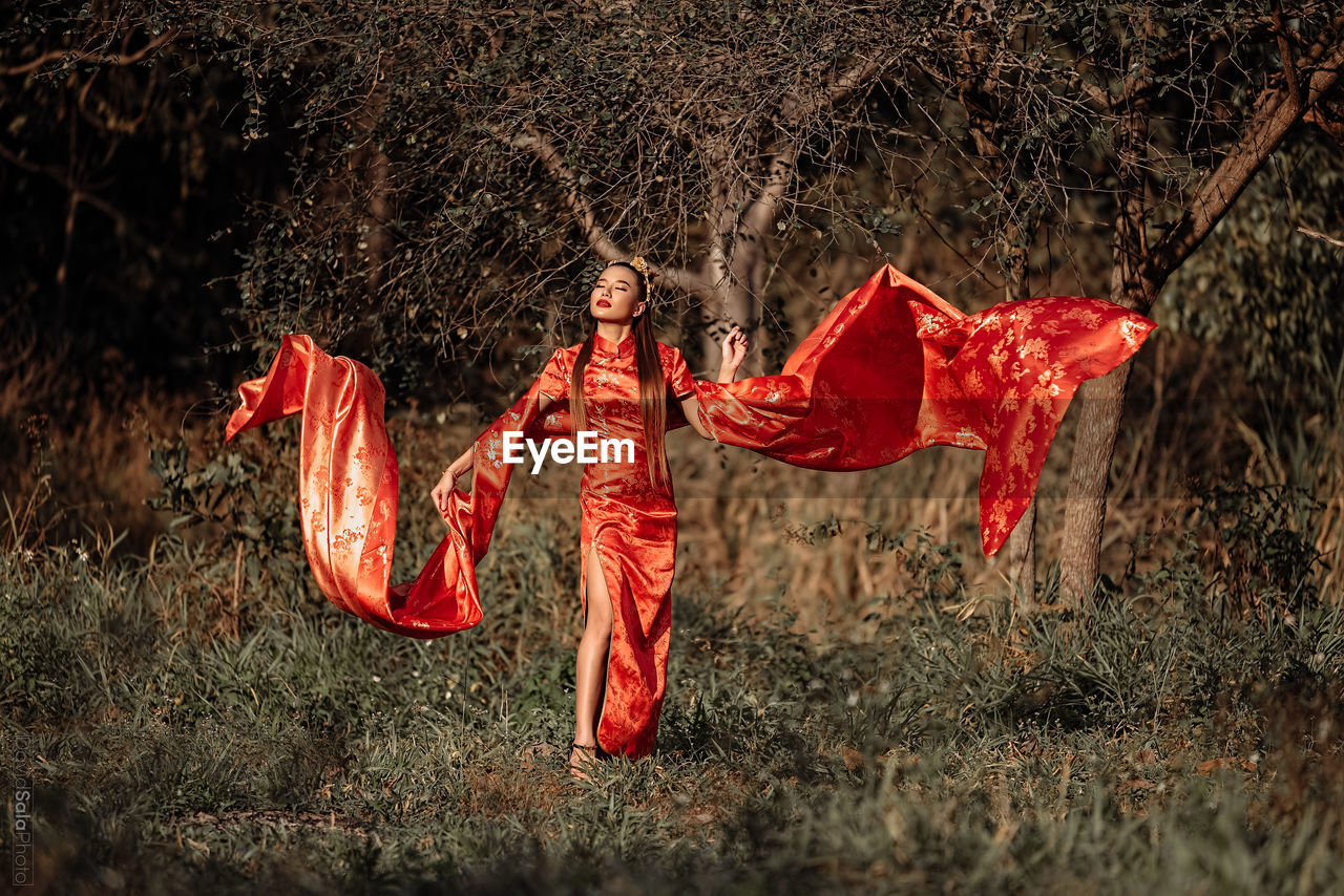 MIDSECTION OF WOMAN HOLDING UMBRELLA IN FOREST