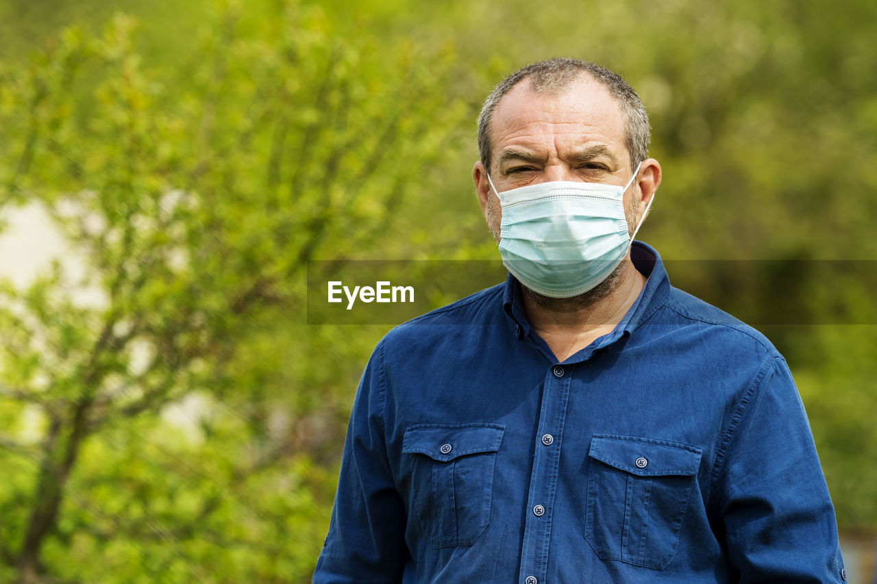 Adult male allergic person in a protective mask on nature