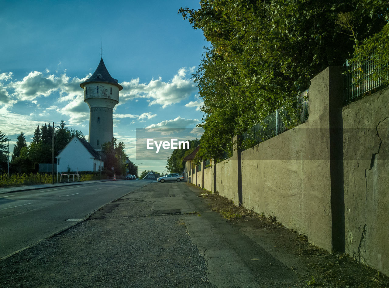 STREET AMIDST TREES AND BUILDINGS AGAINST SKY