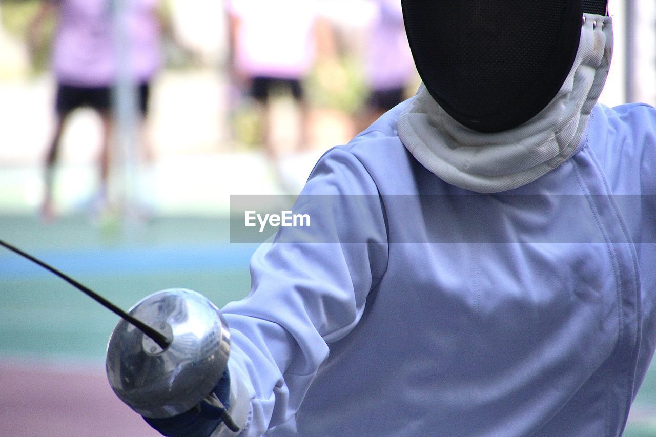 Rear view of man standing on guard for fencing sports 