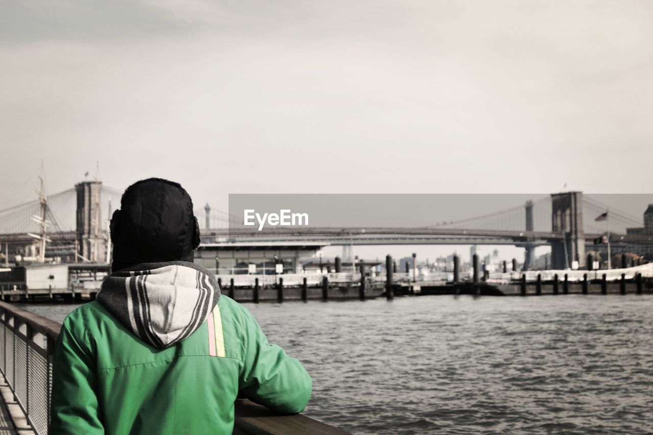 REAR VIEW OF MAN ON SUSPENSION BRIDGE