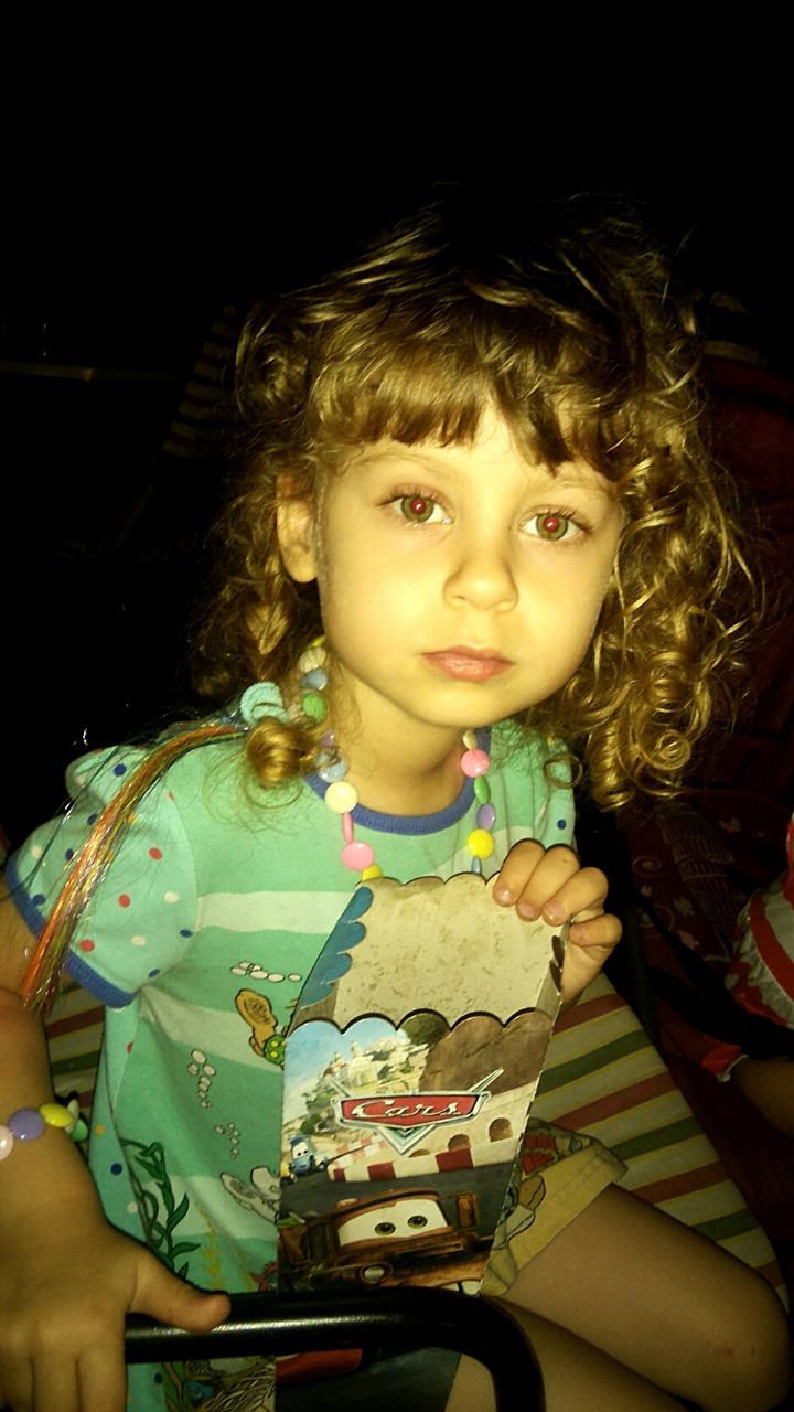 PORTRAIT OF A GIRL SITTING ON BLACK BACKGROUND