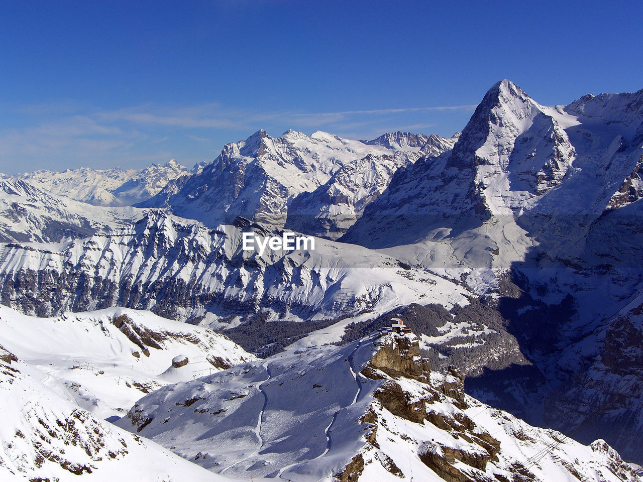 Scenic view of snow covered mountains against blue sky