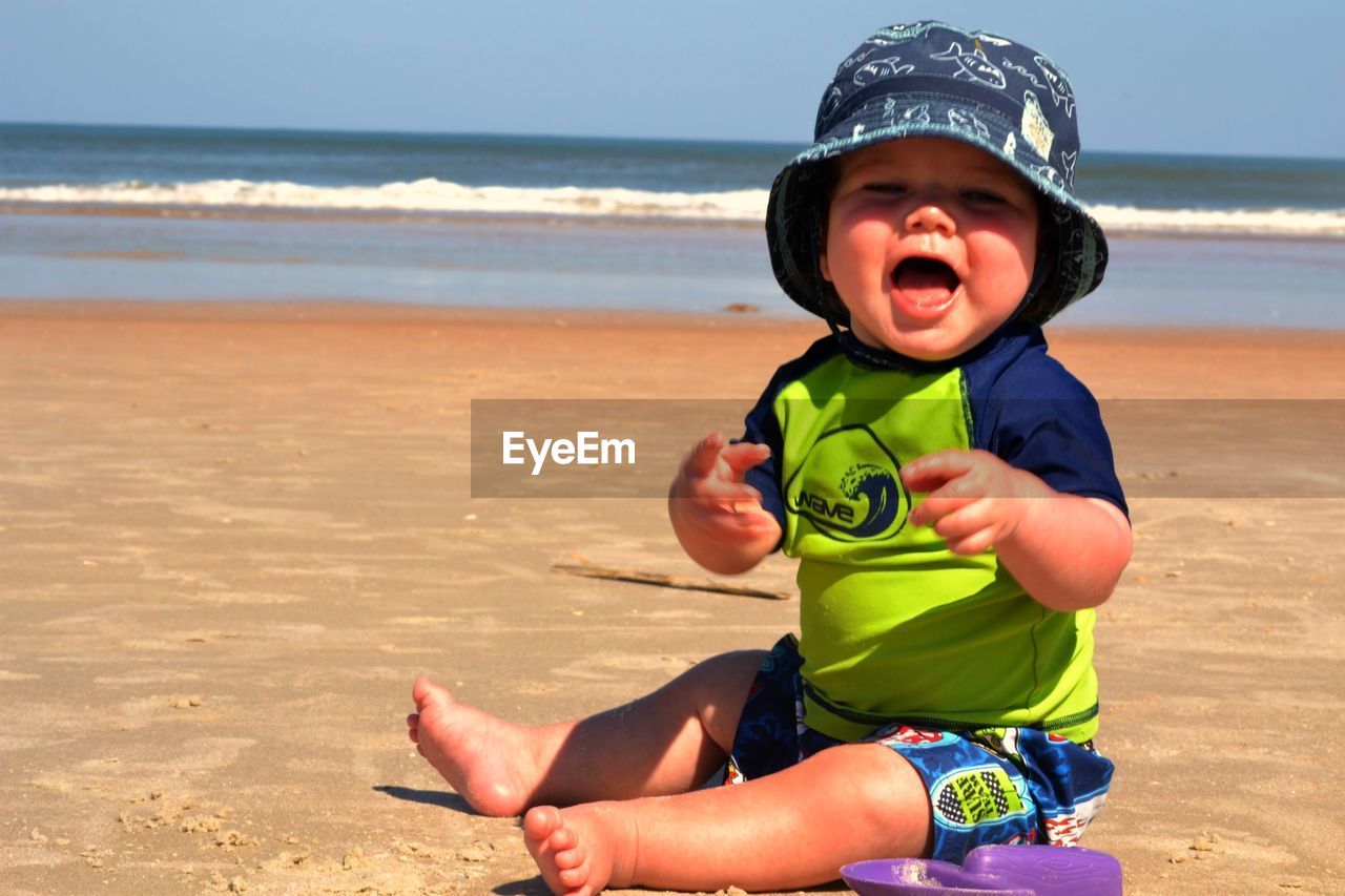 Happy baby boys sitting at beach