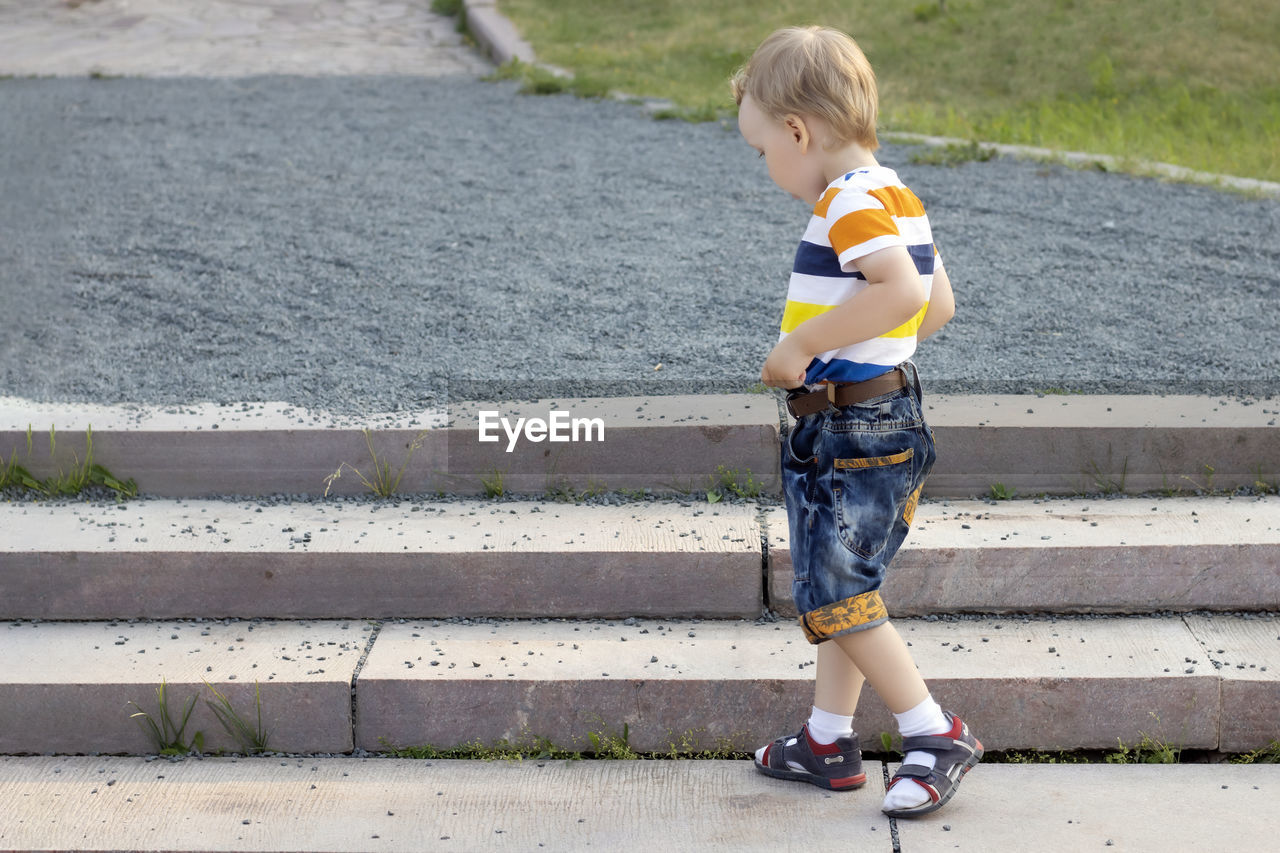 FULL LENGTH OF CUTE BOY LOOKING AWAY WHILE STANDING ON MAN