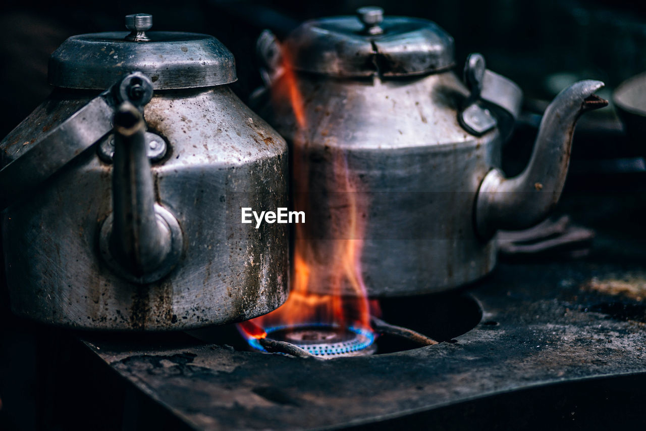 Close-up of kettles on burning stove