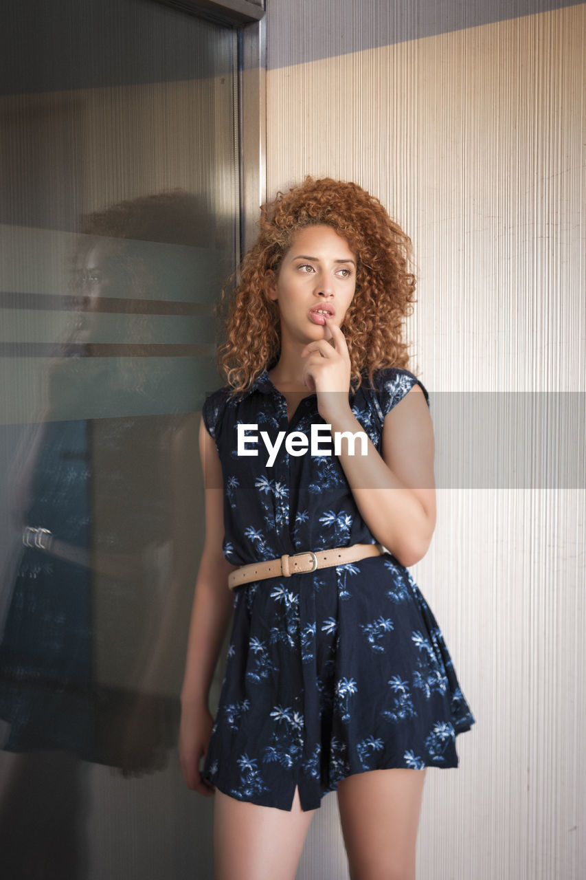 Portrait of young woman standing against wall