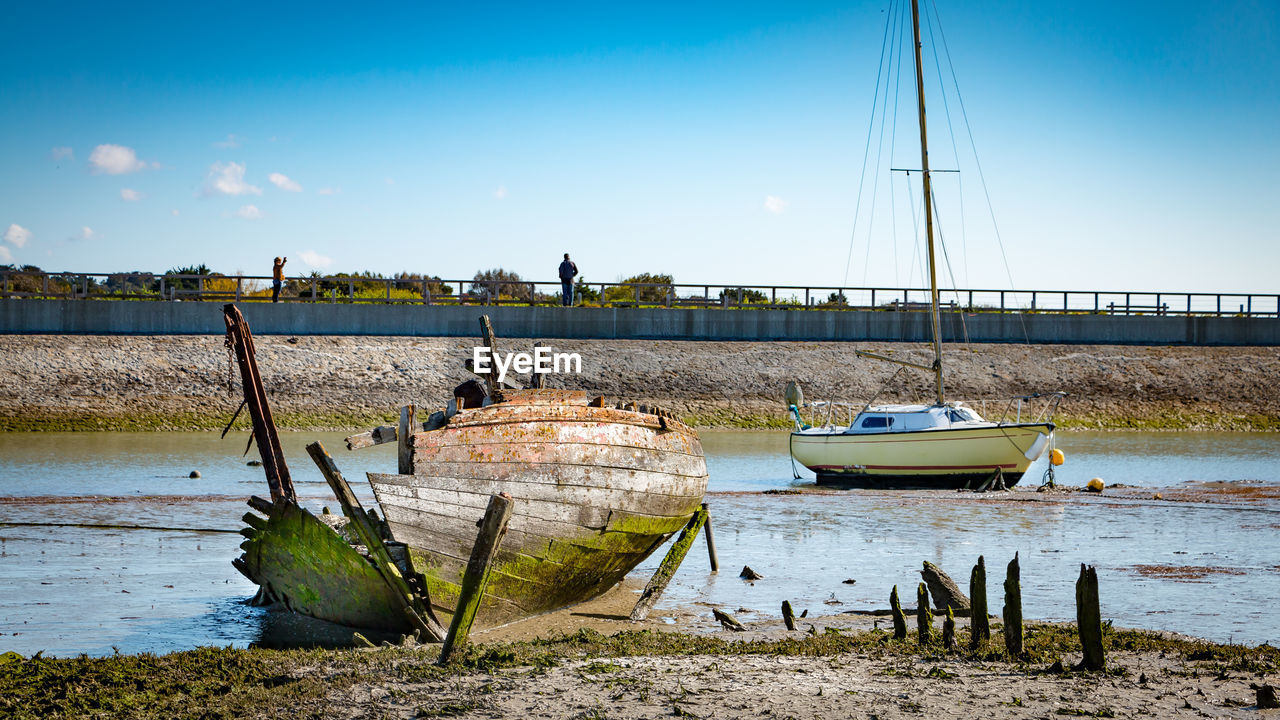 BOATS MOORED ON BEACH AGAINST SKY