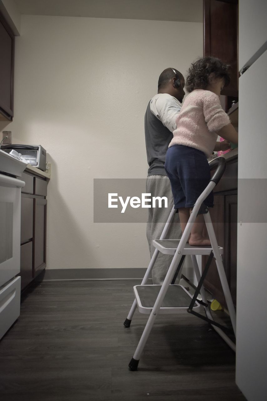 Father and daughter cleaning up dishes together in kitchen