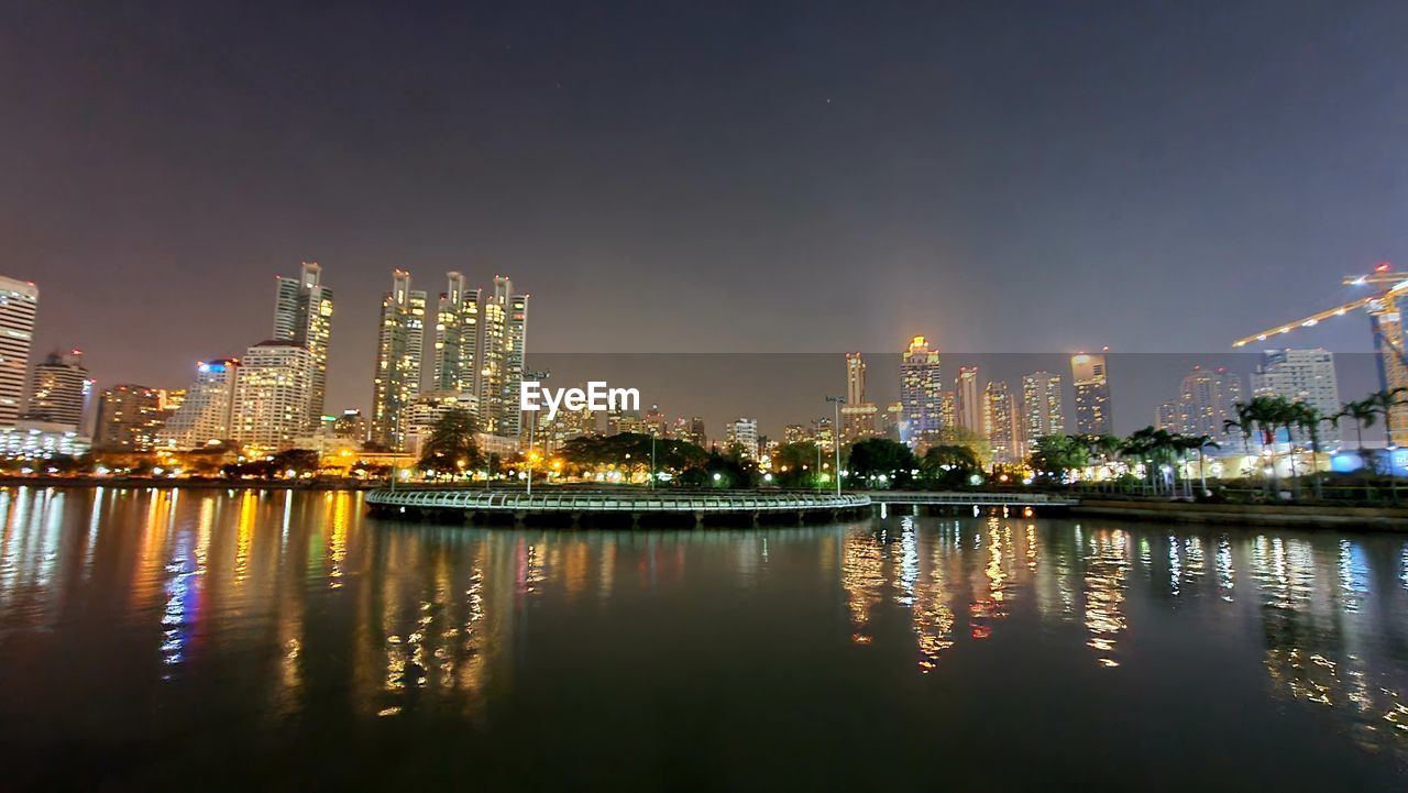 ILLUMINATED BUILDINGS BY CITY AGAINST SKY AT NIGHT