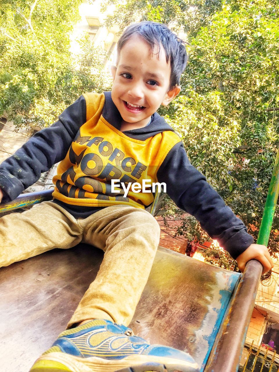 PORTRAIT OF CUTE BOY SITTING IN PARK