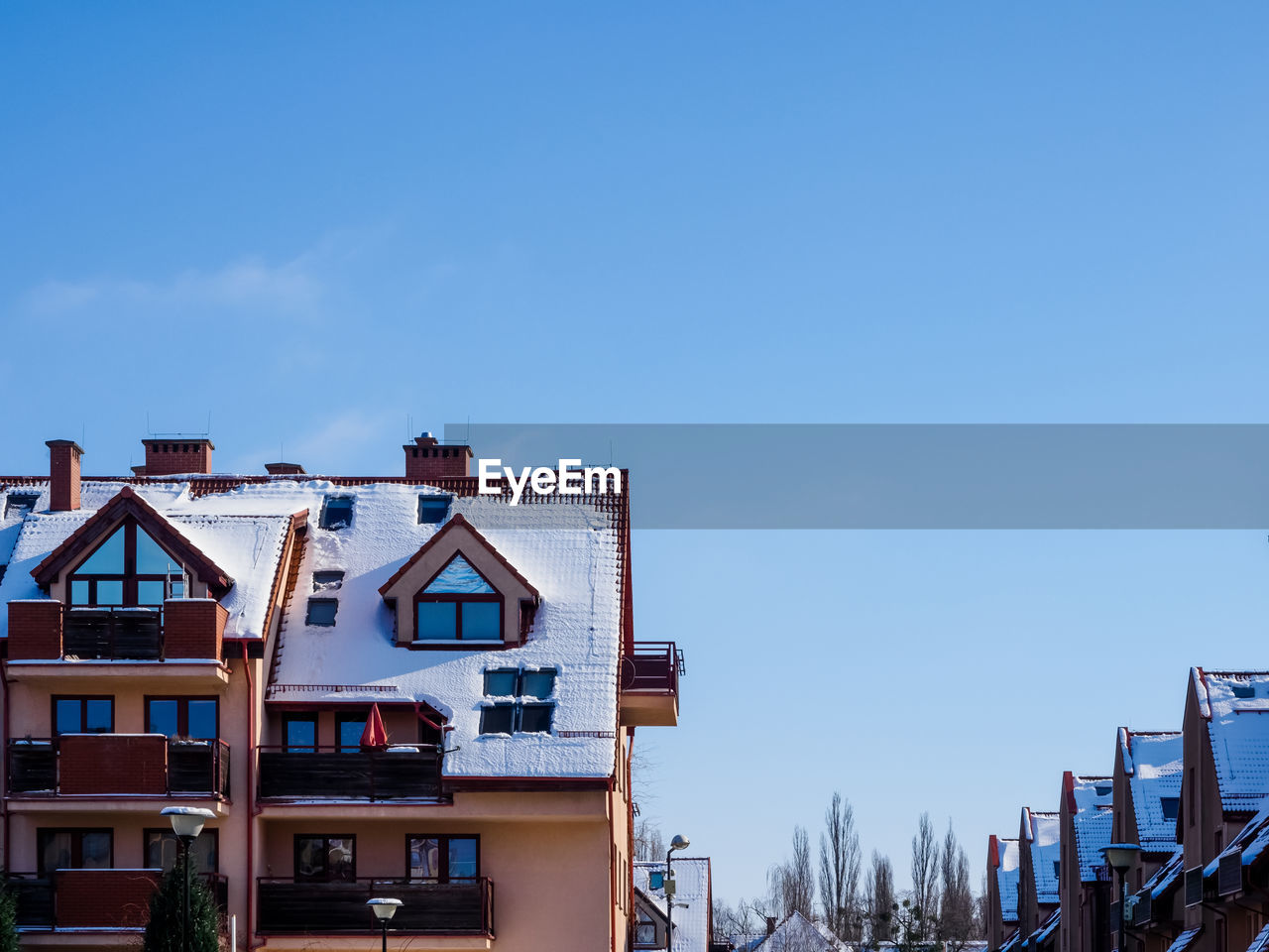 Tenements building roof covered with snow on a blue sky background