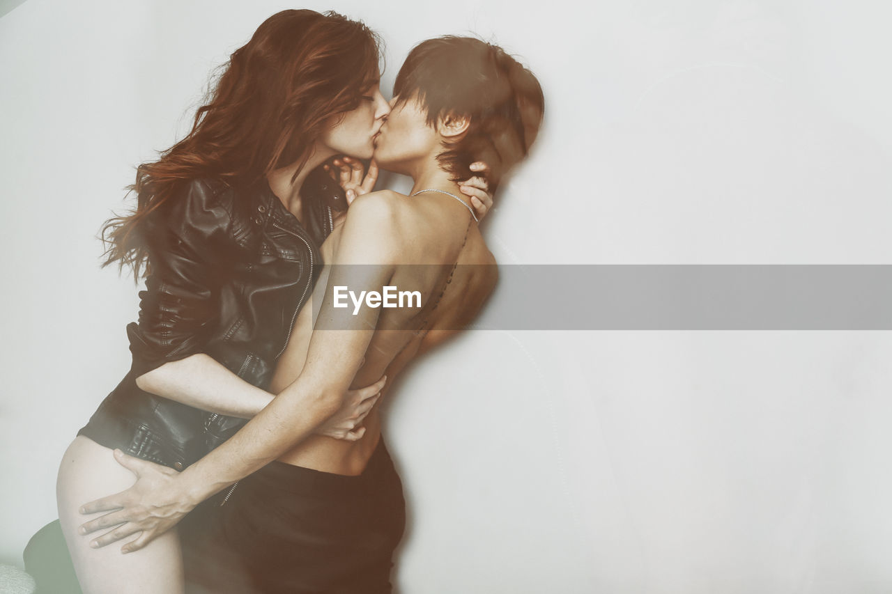 Lesbians kissing against white background