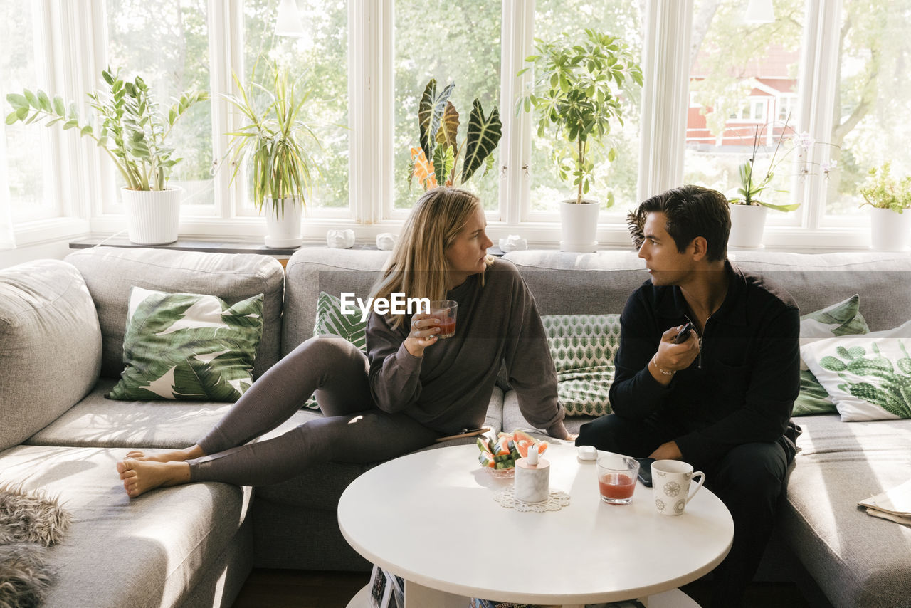 Worried couple talking to each other while sitting on sofa in living room